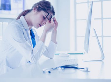 İş yerinde baş ağrısı çeken genç bir kadın doktorun portresi.