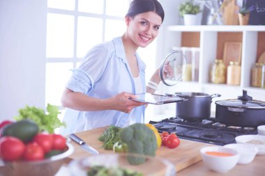 Mutfakta sobanın yanında duran genç bir kadın.