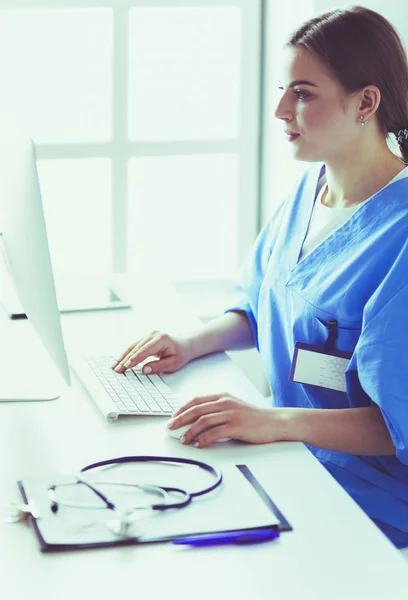 Mladá unavená žena sedí za stolem a pracuje na počítači s lékařskými dokumenty — Stock fotografie