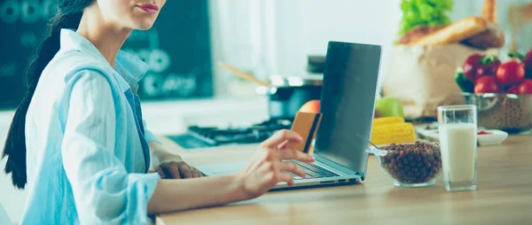 Donna sorridente shopping online con computer e carta di credito in cucina — Foto Stock