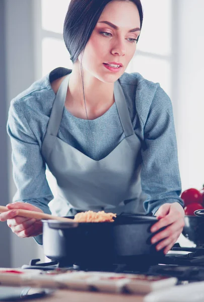 Femme debout près de la cuisinière dans la cuisine, cuisiner et sentir les beaux arômes  . — Photo