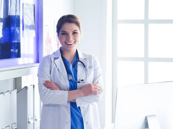 Young woman medic in white uniform standing in clinics office