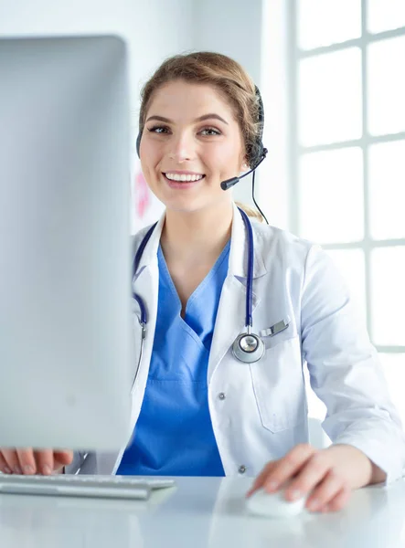 Young practitioner doctor working at the clinic reception desk, she is answering phone calls and scheduling appointments — Stock Photo, Image