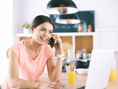 Mutfakta dizüstü bilgisayara benzeyen tariflerle gülümseyen genç bir kadın. Gıda blogcusu kavramı