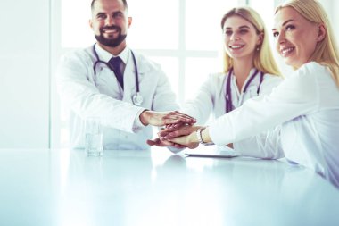 Doktorlar el ele tutuşup yakın çekim yapıyor.