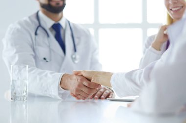 Doktor ofiste erkek bir hastayla el sıkışıyor.