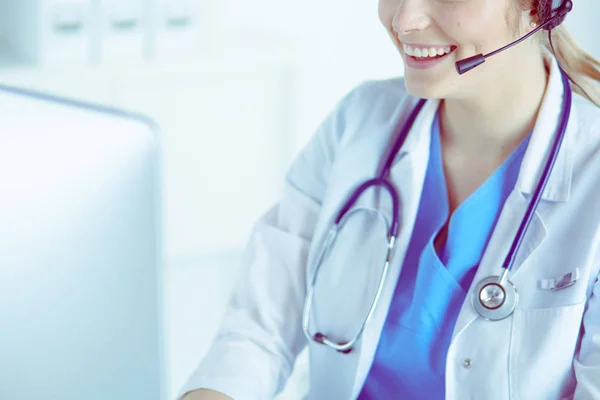 Dokter draagt een headset zittend achter een bureau met laptop — Stockfoto