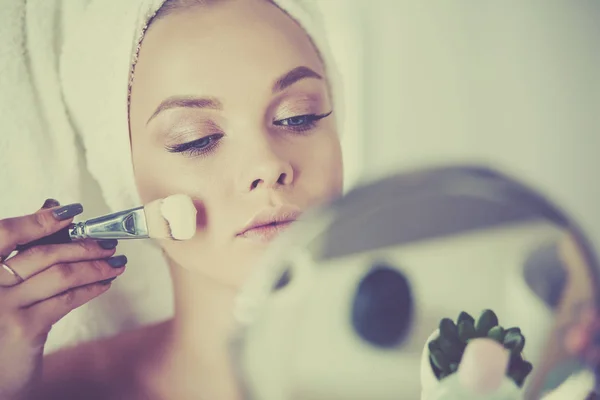 Una foto de una mujer joven aplicando polvo facial en el baño — Foto de Stock