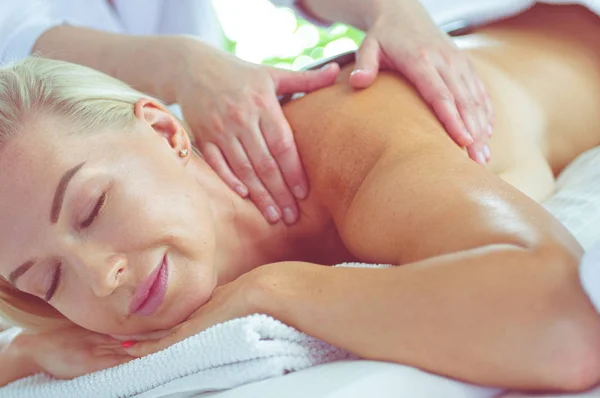 Hermosa mujer spa tumbada sobre una toalla en el salón de spa —  Fotos de Stock