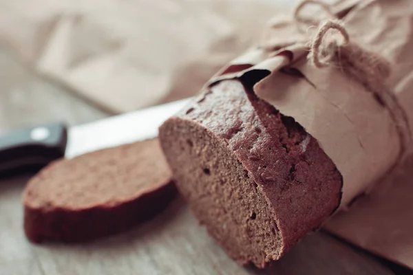 Una pagnotta di pane confezionata in carta su un tavolo di legno — Foto Stock