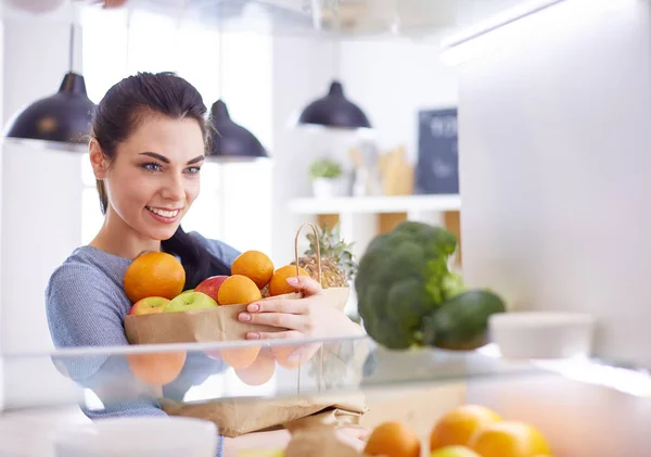 Mujer sonriente sacando una fruta fresca de la nevera, concepto de comida saludable —  Fotos de Stock