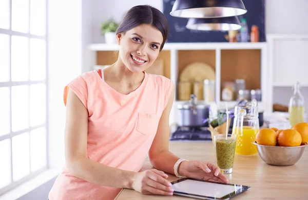 Hermosa joven usando una tableta digital en la cocina —  Fotos de Stock