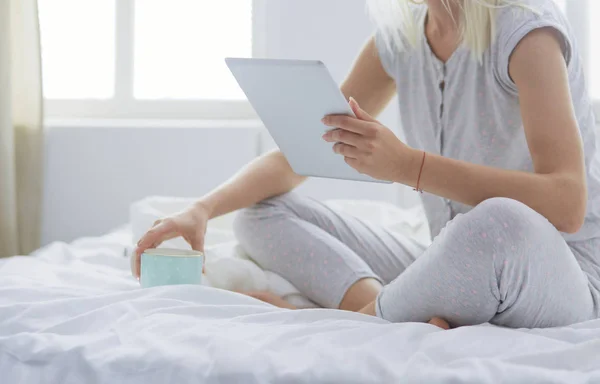 Flicka som håller digital tablett med tom skärm och ler mot kameran i sovrummet — Stockfoto