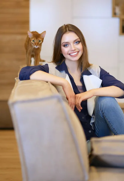 Woman sitting on her white sofa in white pullover — Stock Photo, Image