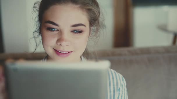 Menina no sofá e websurf em tablet digital — Vídeo de Stock