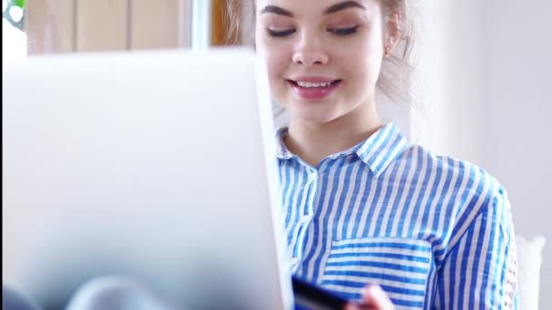 Girll está haciendo el pago en línea. Chica celebración de la tarjeta bancaria utilizando el ordenador portátil moderno — Vídeos de Stock