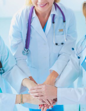 Doktorlar ve hemşireler tıbbi bir ekipte el ele tutuşuyorlar.