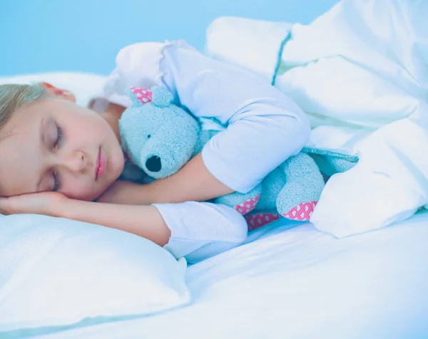 Kleines Mädchen schläft im Bett mit einem Spielzeug-Teddybär. — Stockfoto