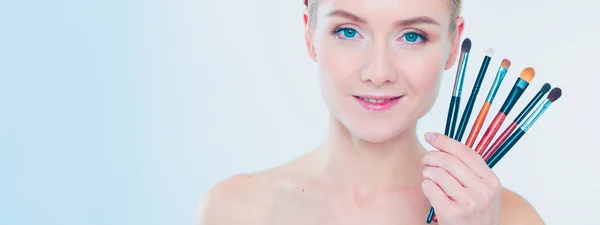 Portret van mooi jong meisje op witte achtergrond met een perfecte gezicht met veel handen met make-up borstel. — Stockfoto