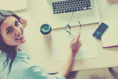 Dizüstü bilgisayar ekranına bakarak office tablosunda oturan genç kadın