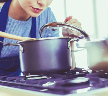 Mutfakta ahşap kaşıkla yemek pişiren kadın
