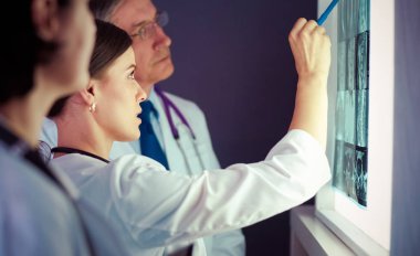 Bir grup doktor bir klinikte röntgenleri inceliyor, teşhis koymayı düşünüyorlar.