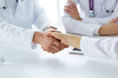 Doktorlar el ele tutuşup yakın çekim yapıyor.