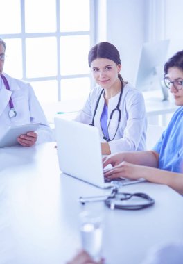 Ciddi bir tıbbi ekip hastaları parlak bir ofiste tartışıyor.