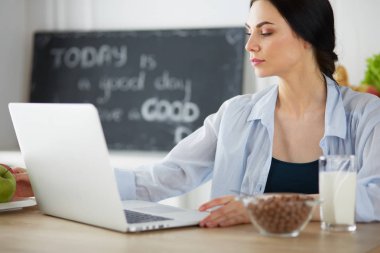 bir fincan kahve ve bir dizüstü bilgisayar mutfakta bir kadınla