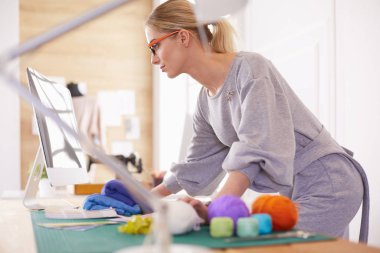 Bir dizüstü bilgisayar kullanarak ve gülümseyen bir genç Asyalı tasarımcı kadın portresi, elbise arka plan olarak astı.