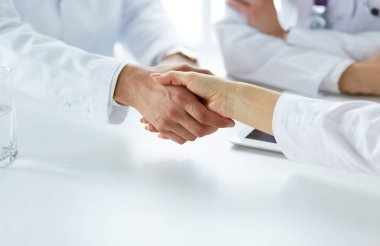 Doktorlar el ele tutuşup yakın çekim yapıyor.