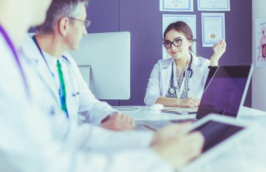 Ciddi bir tıbbi ekip parlak bir ofiste dizüstü bilgisayar kullanıyor.