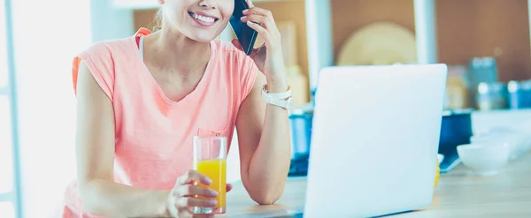 Giovane donna in cucina con computer portatile alla ricerca di ricette, sorridente. Concetto di food blogger — Foto Stock