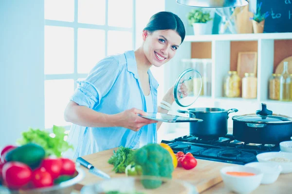 Mujer joven parada junto a la estufa en la cocina —  Fotos de Stock