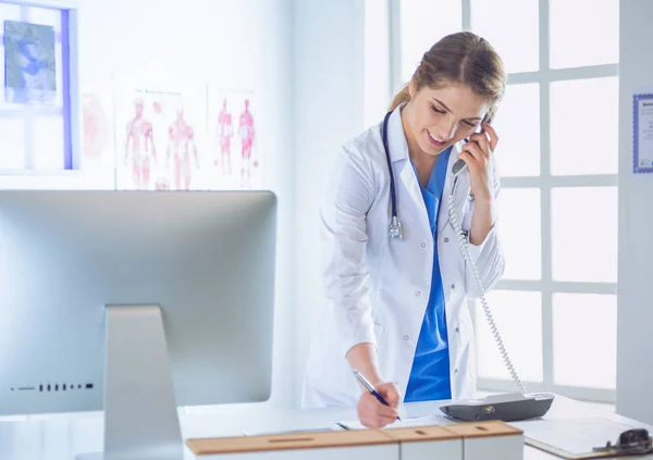 Serious doctor on the phone in her office — Stock Photo, Image