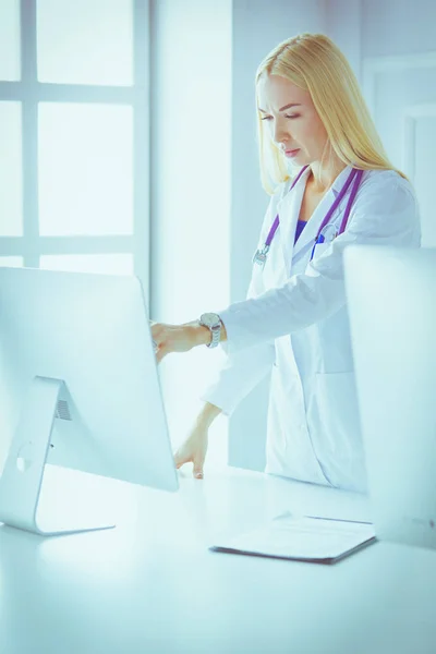 Hastane ofisindeki bilgisayara işaret ederken iş yerindeki genç kadın doktor. — Stok fotoğraf