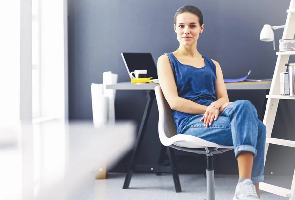 Jonge vrouw zit aan het bureau met instrumenten, plan en laptop. — Stockfoto