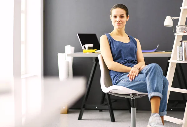 Jonge vrouw zit aan het bureau met instrumenten, plan en laptop. — Stockfoto