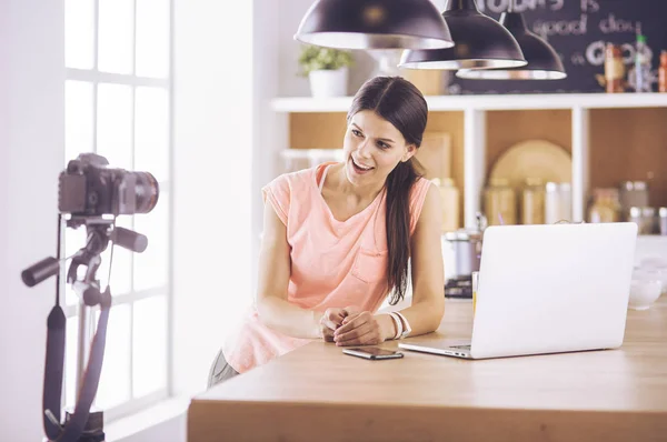 Ung kvinna i köket med bärbar dator ser recept, leende. Begreppet livsmedelsbloggare — Stockfoto