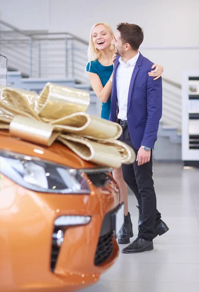 Muž dává dárek - auto své ženě. To ji překvapuje. Mají z toho velkou radost. — Stock fotografie