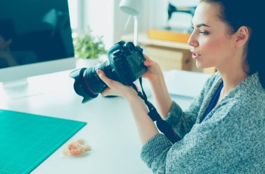 İşyerinin yanında duran ve dijital fotoğraf makinesinde fotoğraflayan genç kadın tasarımcı