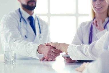 Doktor ofiste erkek bir hastayla el sıkışıyor.