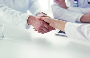 Doktorlar el ele tutuşup yakın çekim yapıyor.