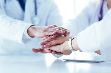 Doktorlar el ele tutuşup yakın çekim yapıyor.
