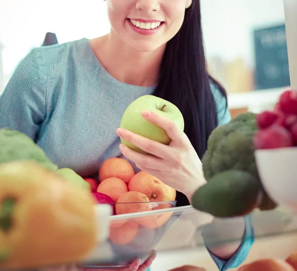 Mujer sonriente sacando una fruta fresca de la nevera, concepto de comida saludable —  Fotos de Stock