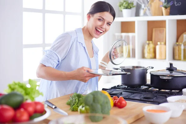 Jeune femme debout près de la cuisinière dans la cuisine — Photo