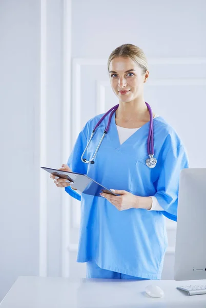 Médico sonriente con una carpeta en uniforme de pie —  Fotos de Stock