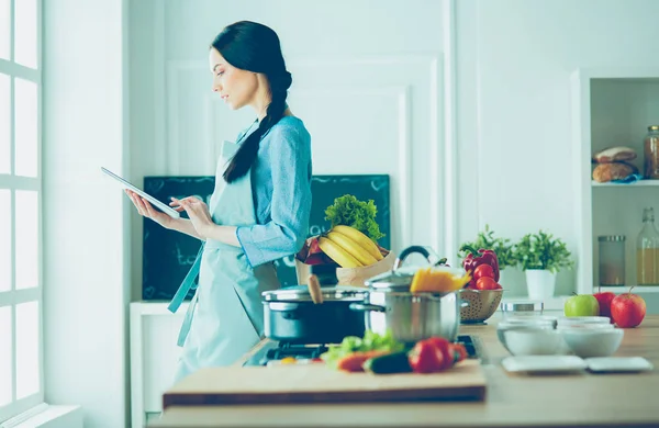 Junge Frau kocht mit Tablet-Computer in ihrer Küche — Stockfoto