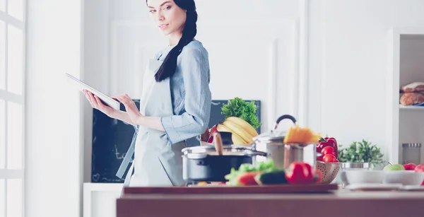 Mujer joven usando una tableta para cocinar en su cocina — Foto de Stock