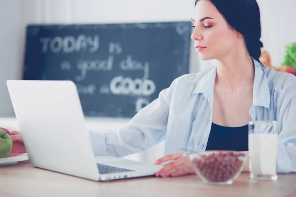 Donna con una tazza di caffè e un computer portatile in cucina — Foto Stock